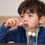 Young child taking a calcium tablet with a glass of water